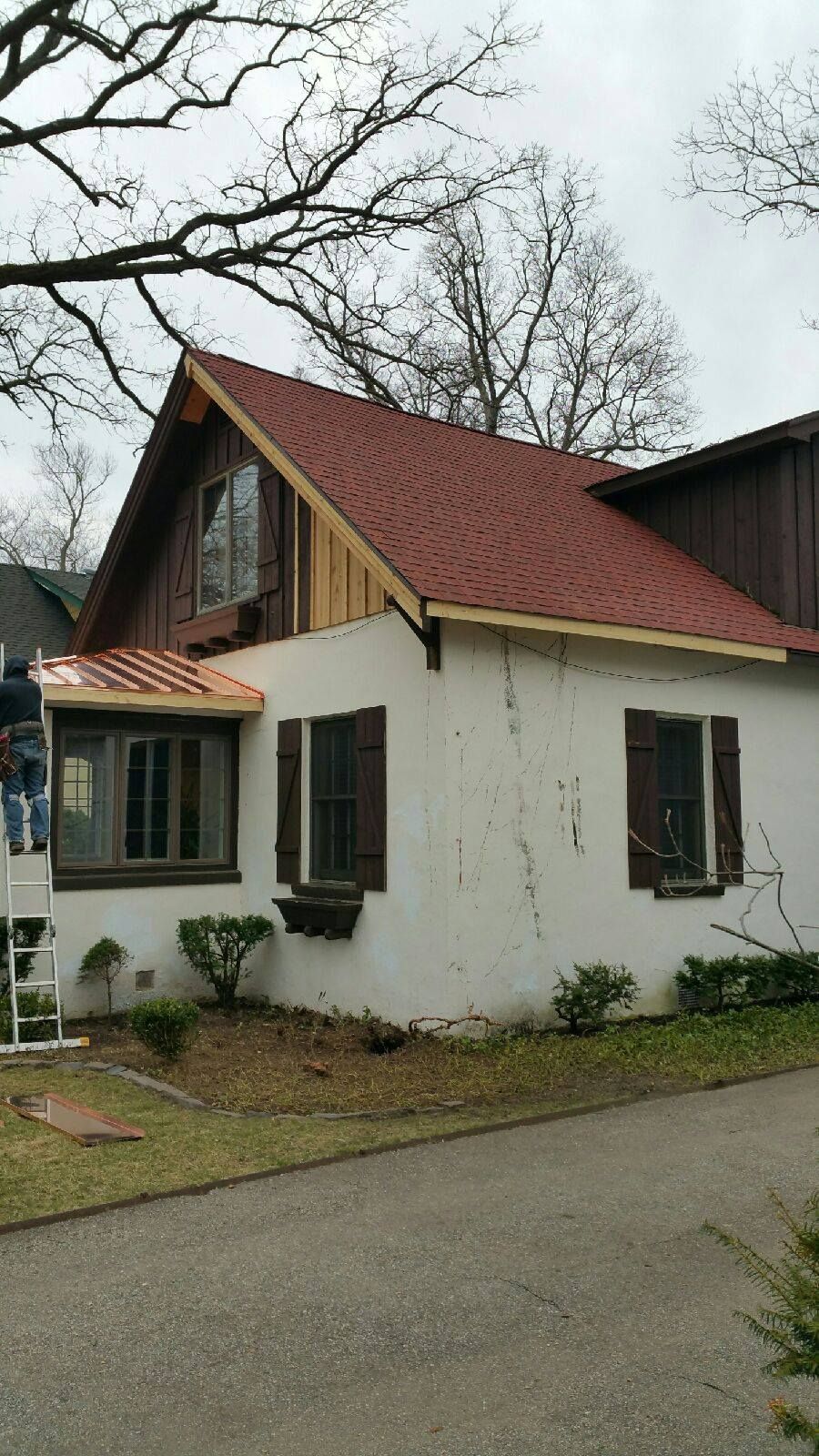 A white house with a red roof and brown shutters