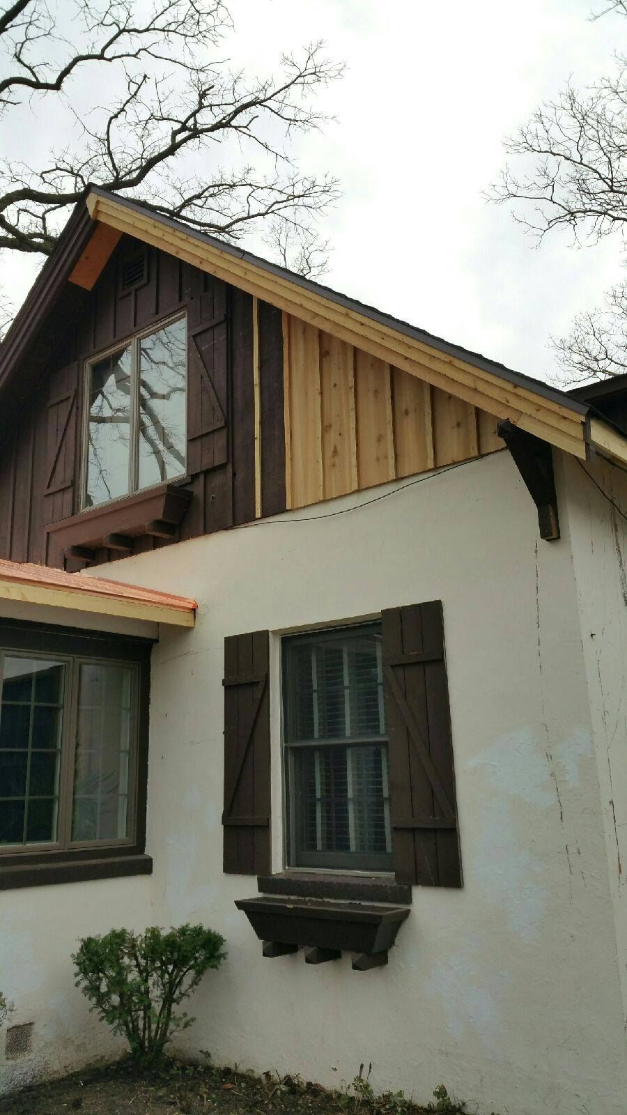 A white house with a wooden siding and brown shutters.