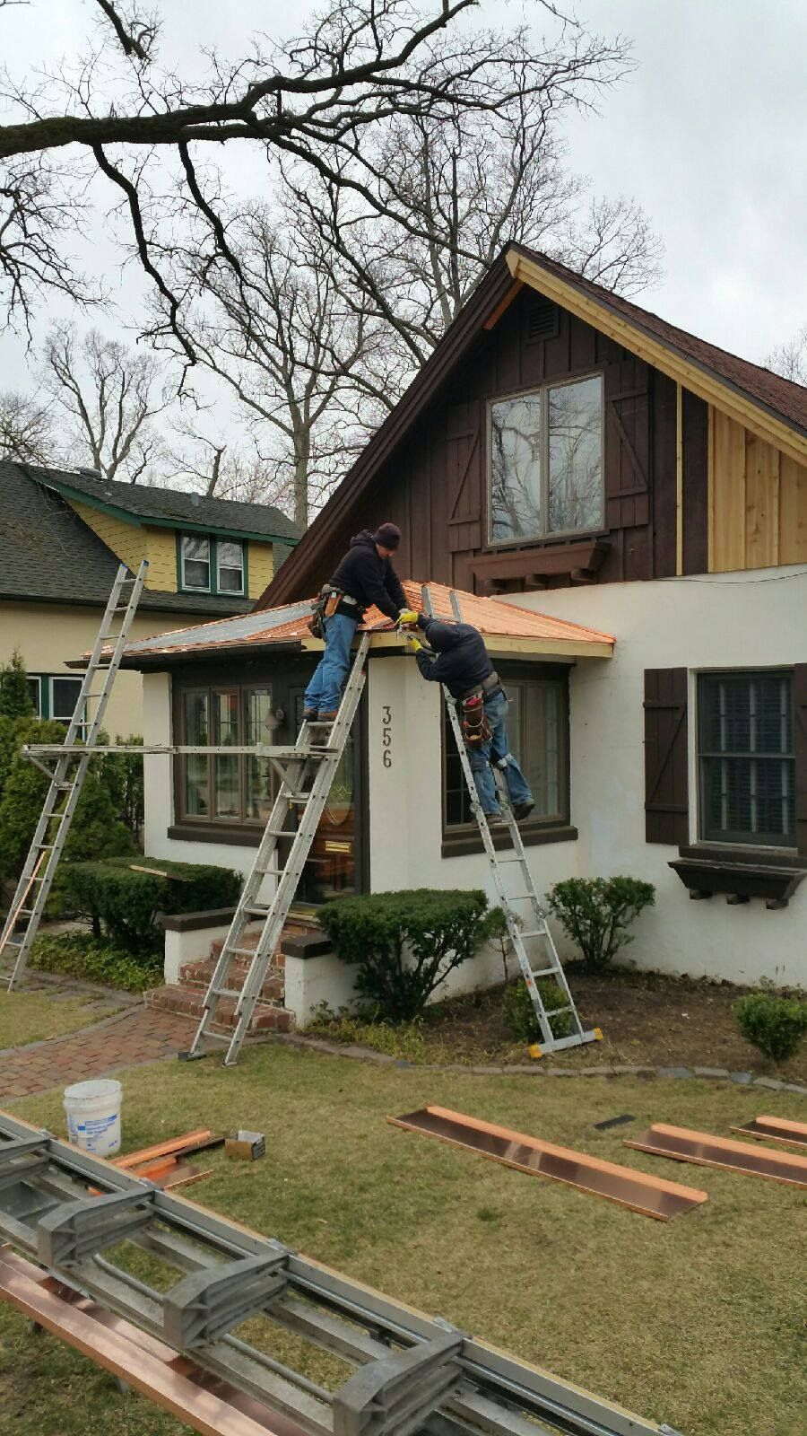 Two men are working on the roof of a house.