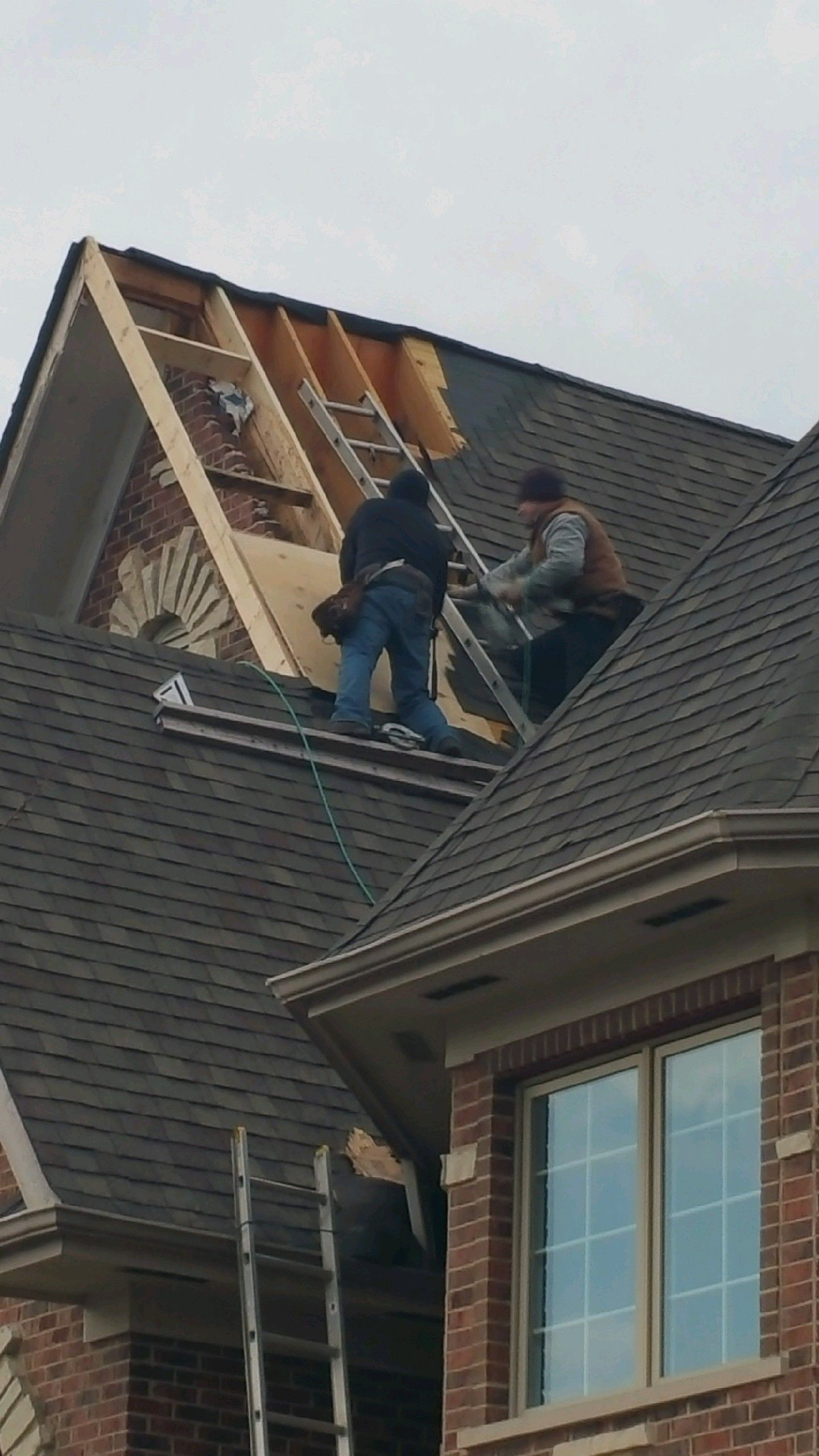 Two men are working on the roof of a house.