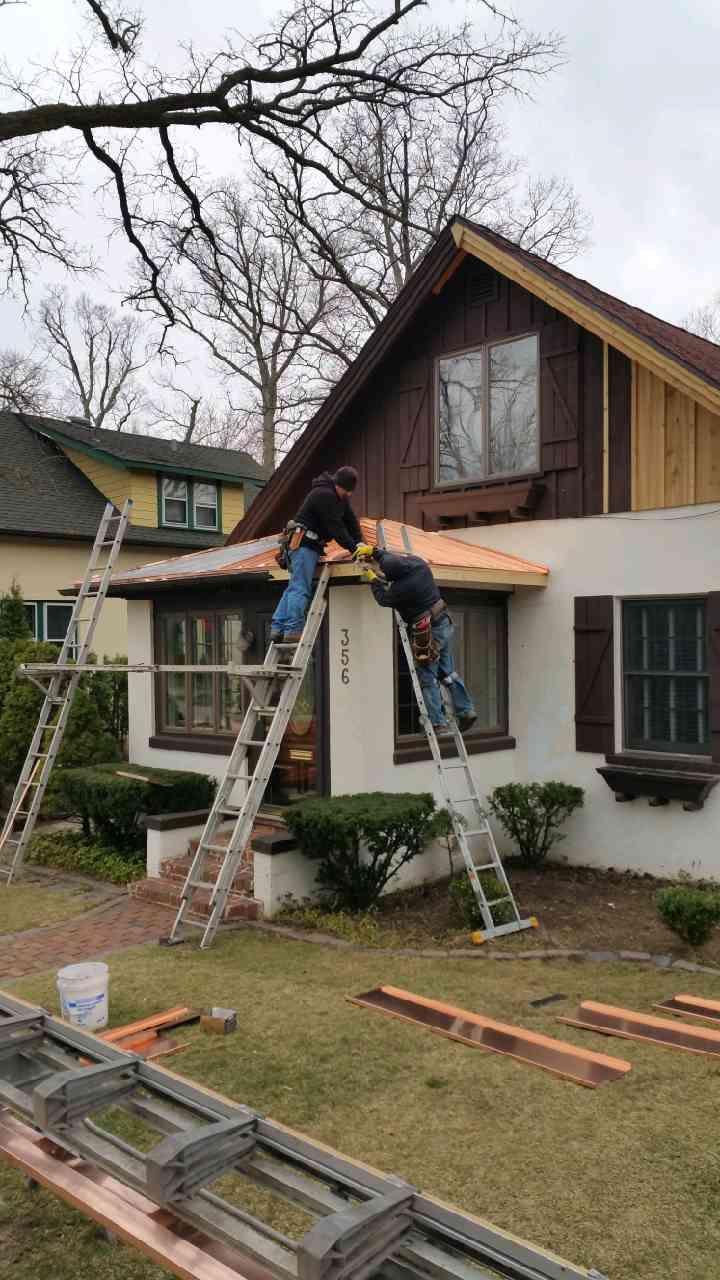 A group of men are working on the roof of a house.