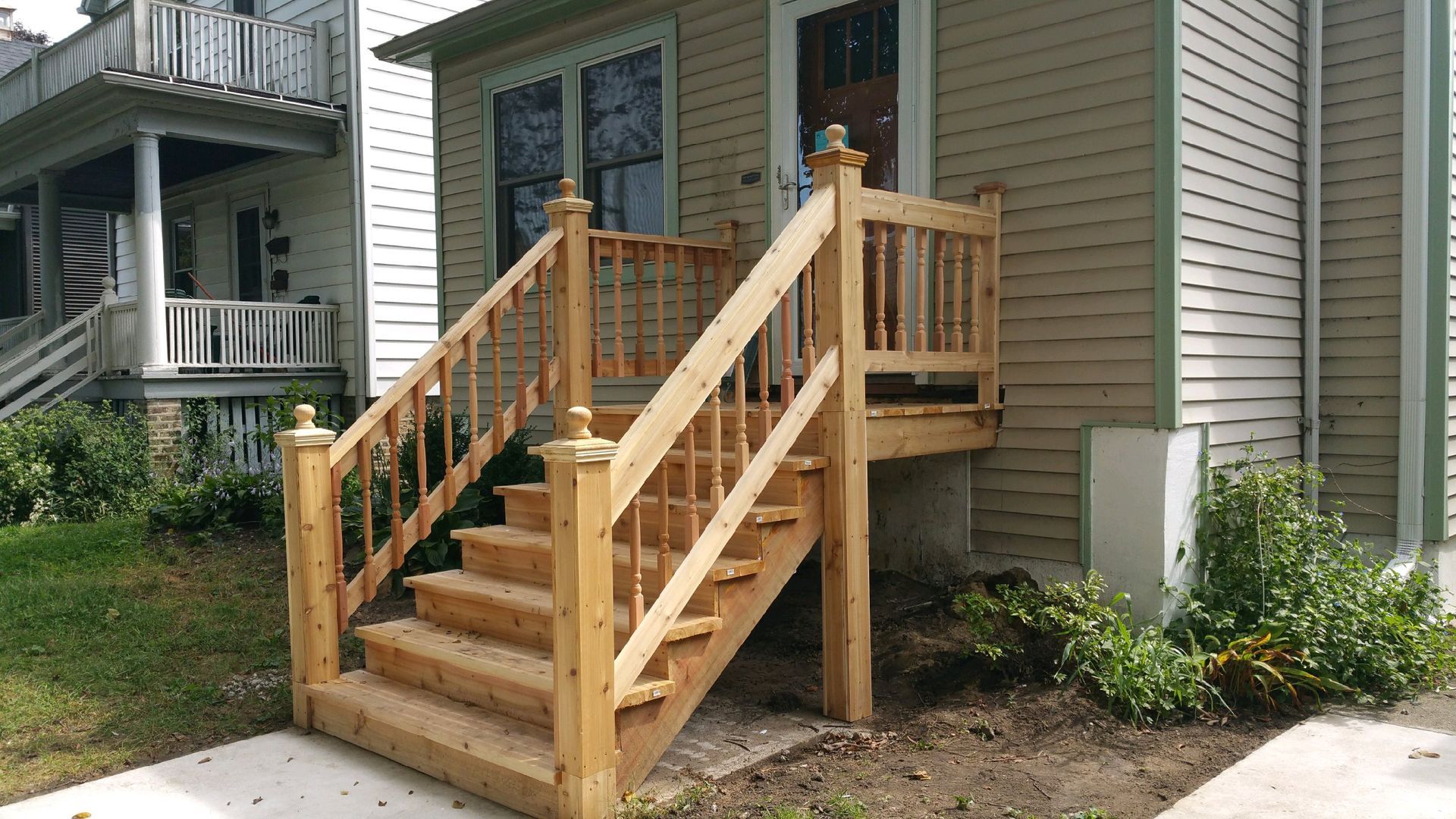 A wooden deck with stairs leading up to the front of a house.