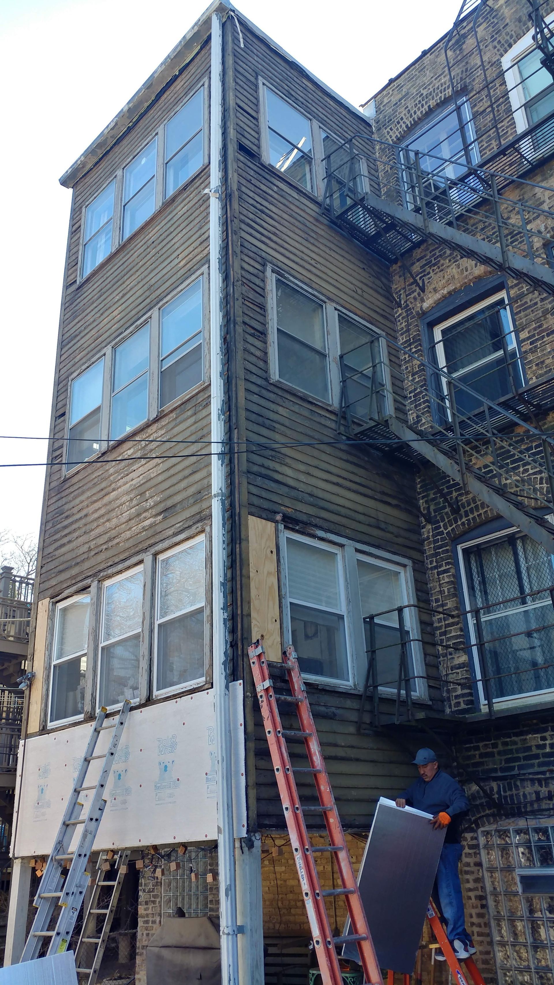 A man is standing on a ladder in front of a building.