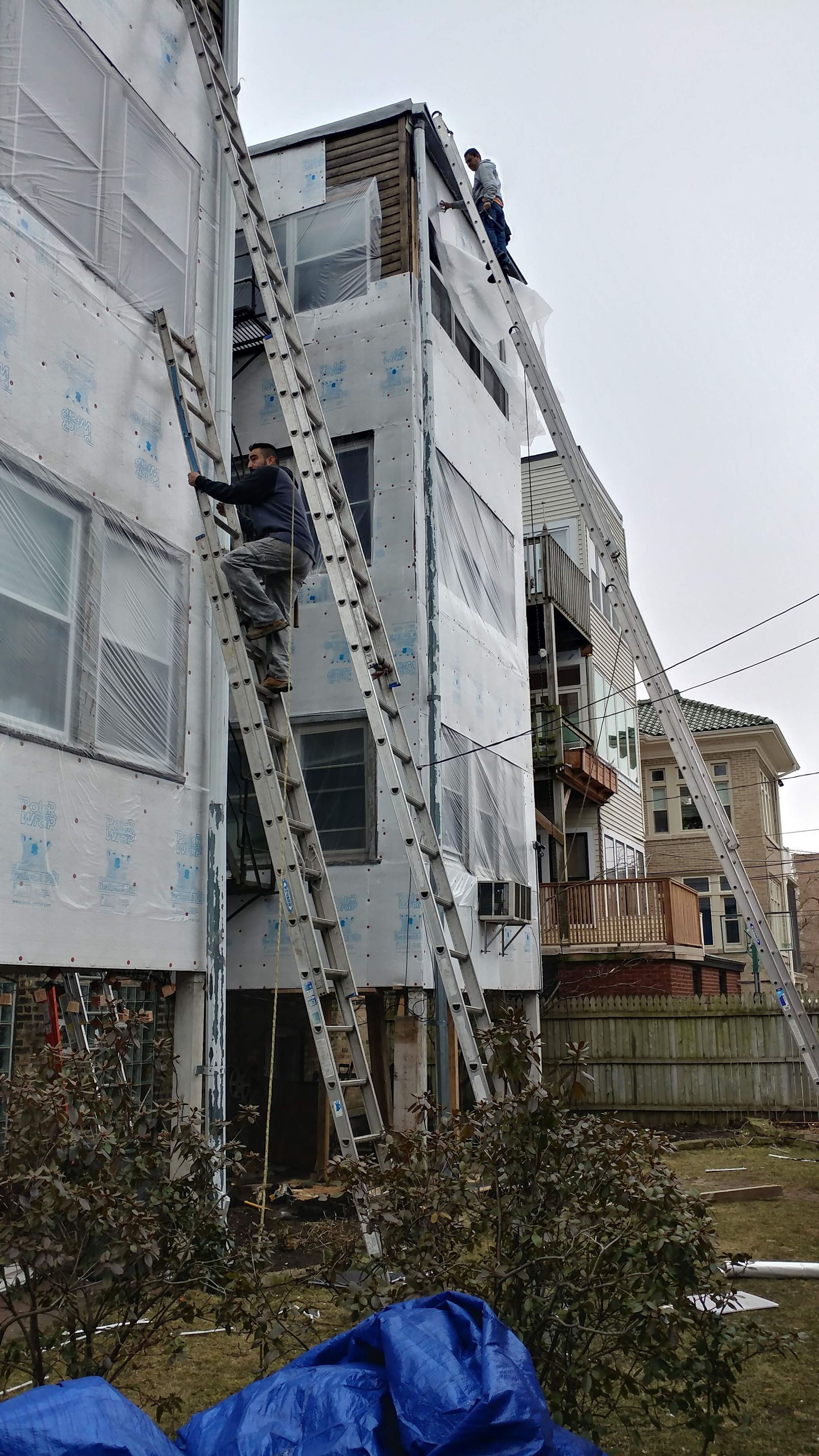 A man is standing on a ladder on the side of a building.
