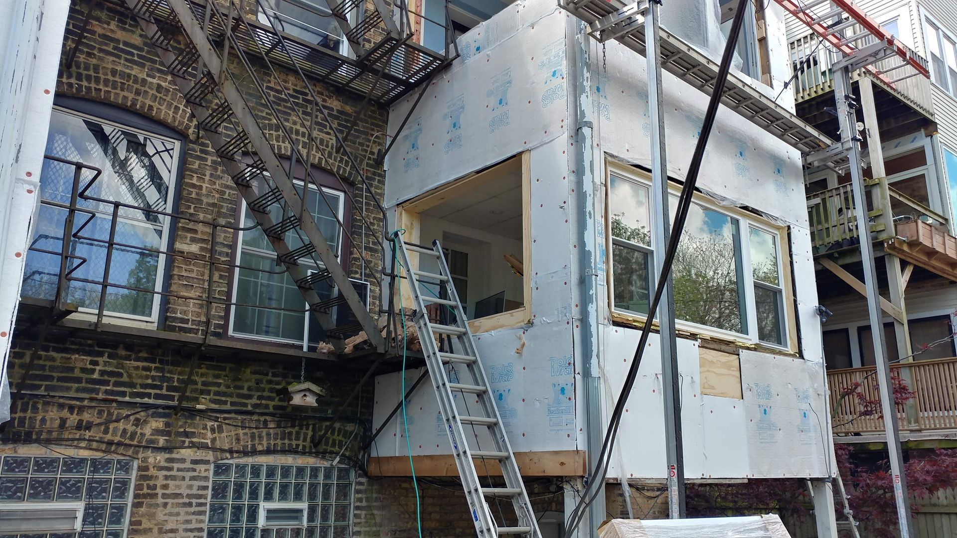 A brick building with a fire escape is being remodeled.