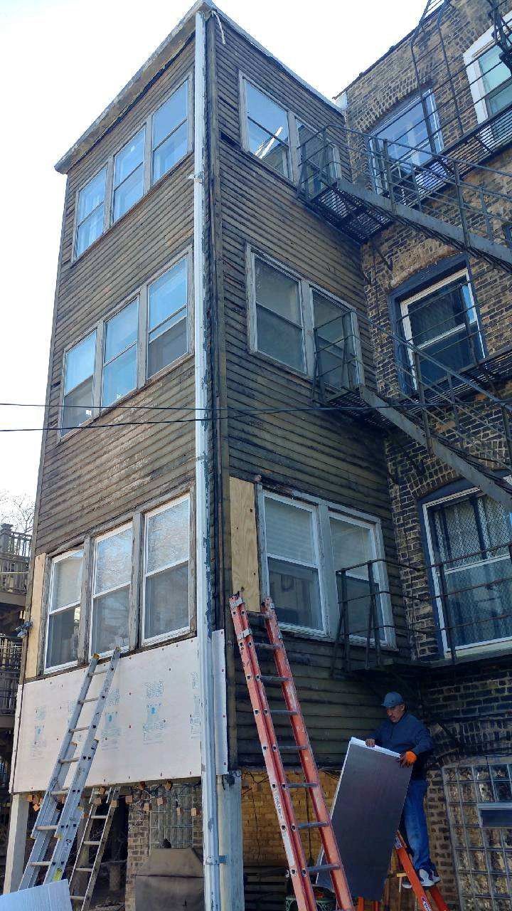 A man is standing on a ladder in front of a building.