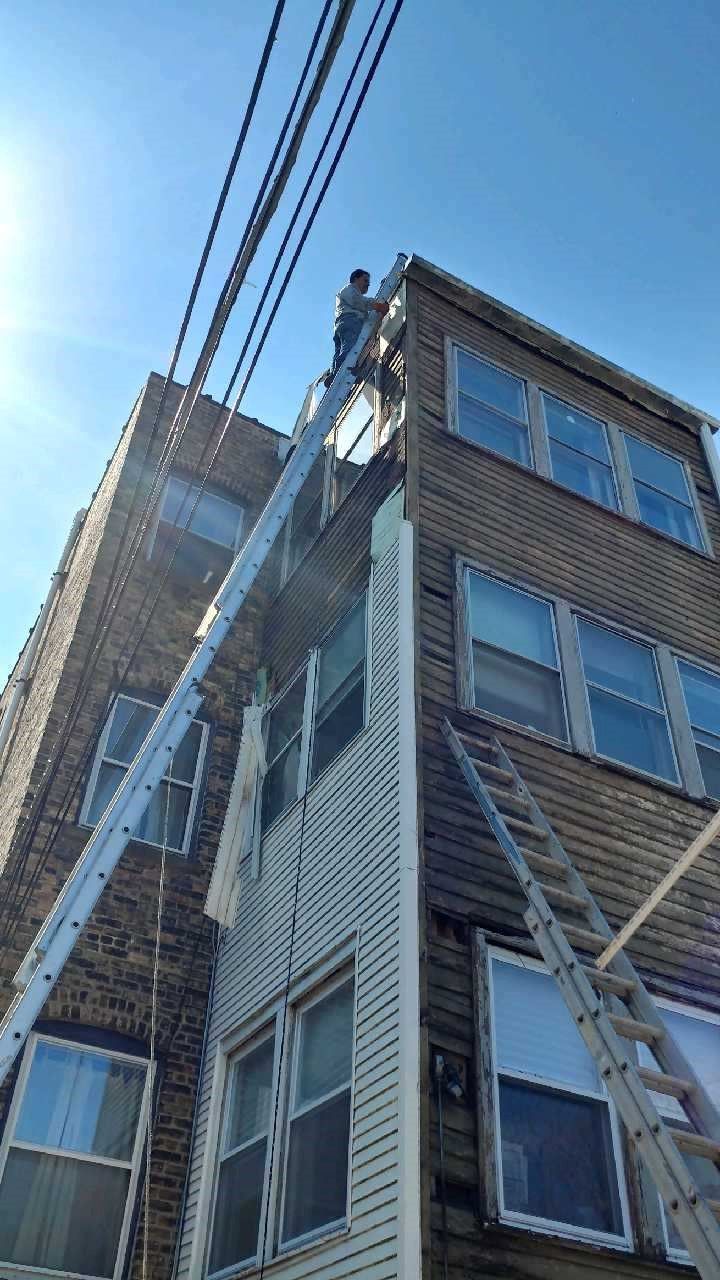 A man is standing on a ladder on the side of a building.