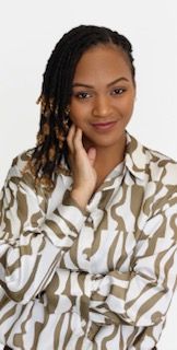 A woman is sitting at a desk with a laptop and a vase of flowers.