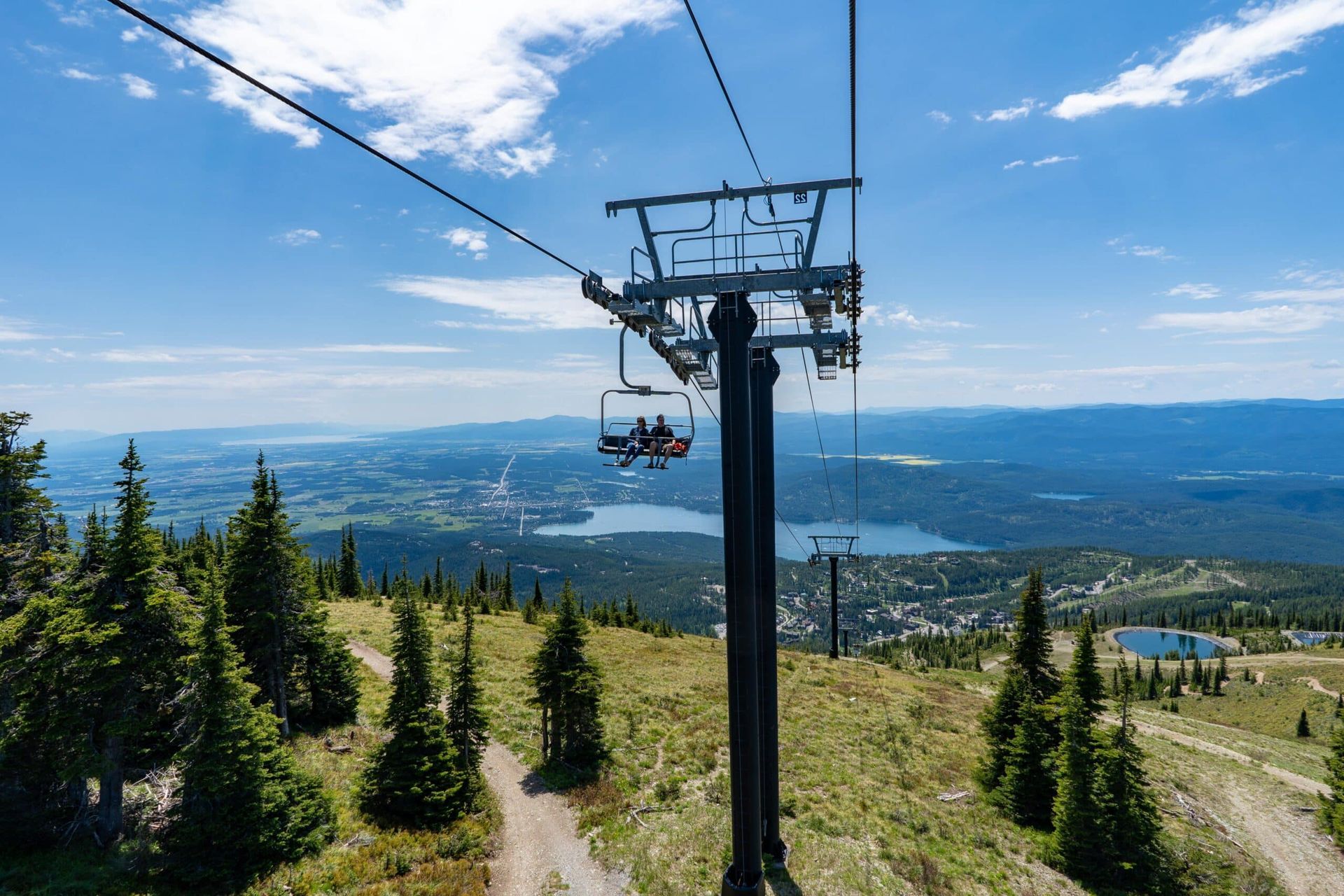 Two people are riding a ski lift up a mountain.