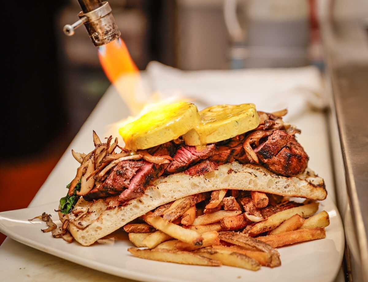 A hamburger and a salad on a white plate on a table.