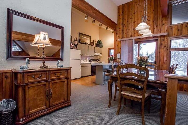 A dining room with a table and chairs and a mirror