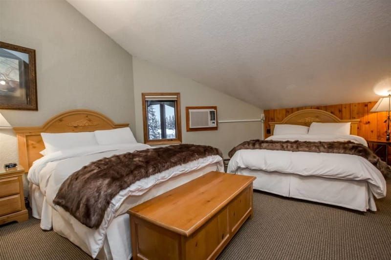 A hotel room with two beds and a bench