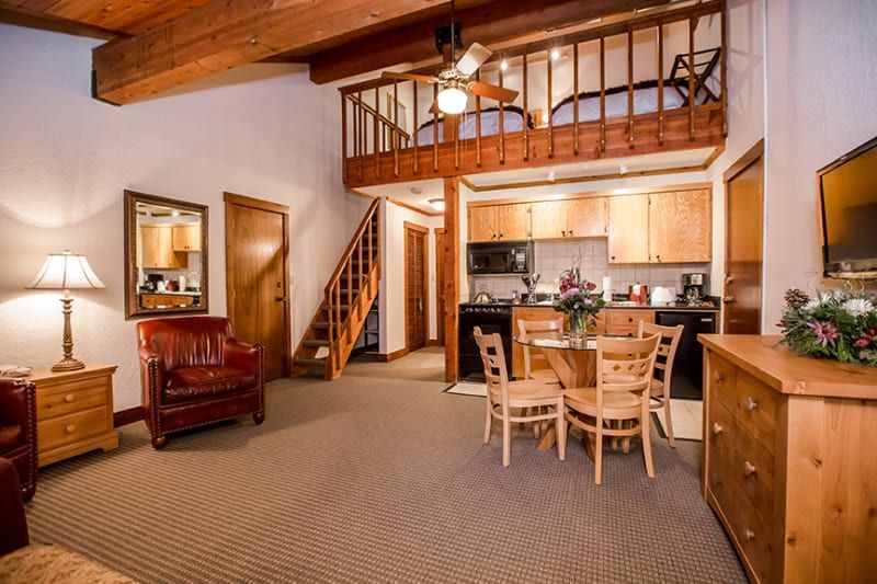 A living room with a dining table and chairs and a kitchen.