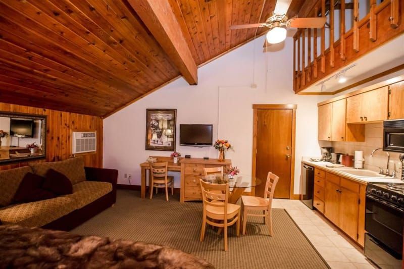 A living room with a couch , table , chairs and a ceiling fan.