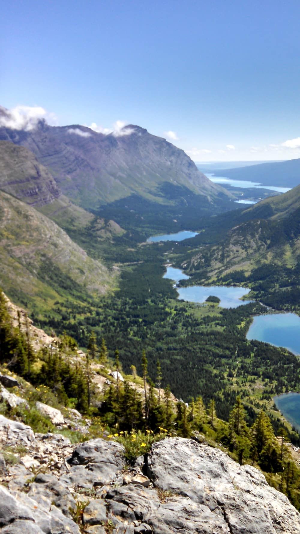A view of a valley surrounded by mountains and lakes from the top of a mountain.