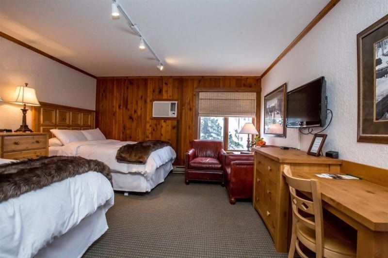 A hotel room with two beds , a desk , chairs and a television.