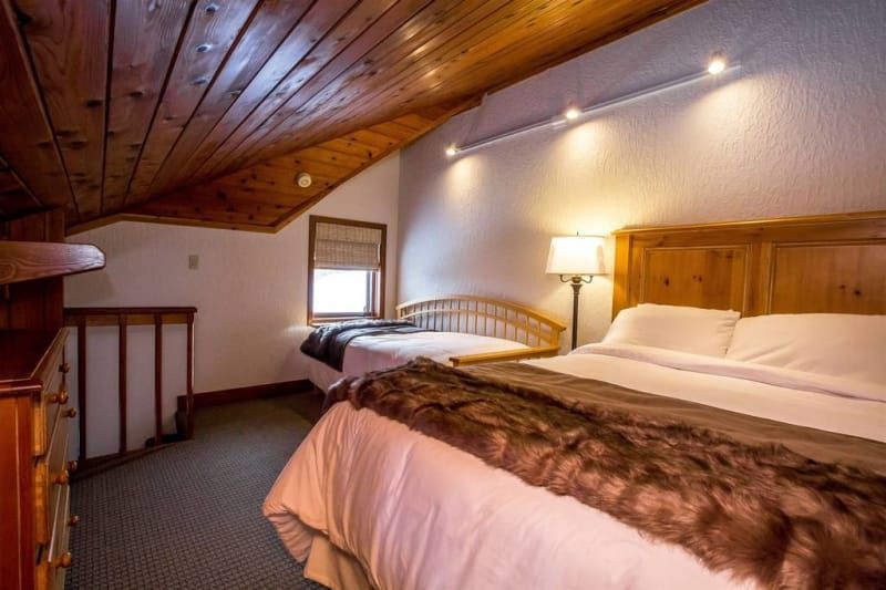 A bedroom with two beds and a wooden ceiling.
