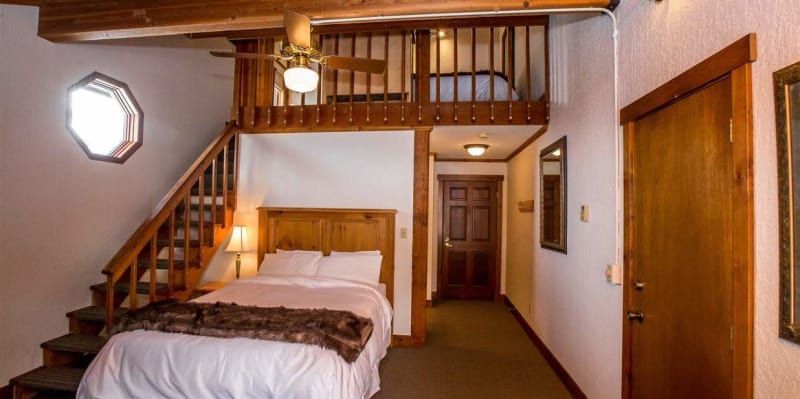 A bedroom with a bed , stairs and a balcony.