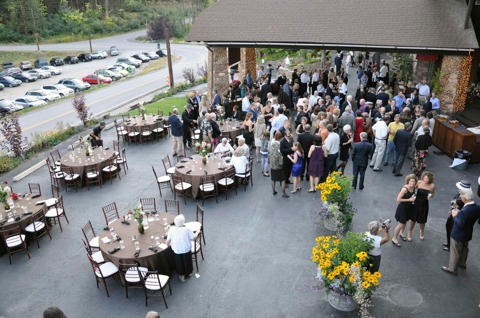 A large group of people are gathered on a patio with tables and chairs