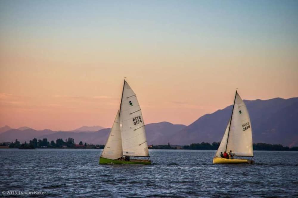 Two sailboats are in the water with mountains in the background