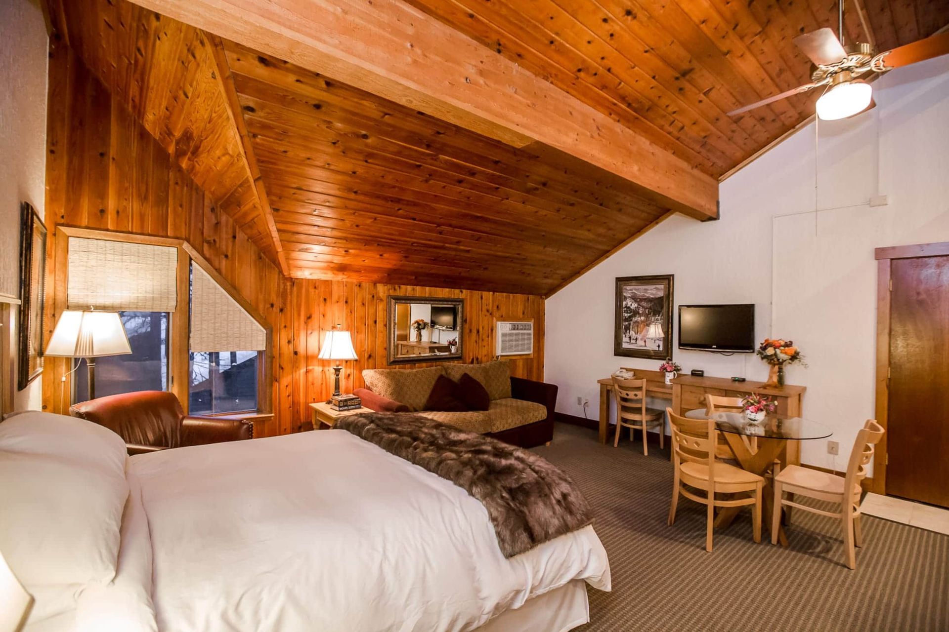 A hotel room with a king size bed and a ceiling fan