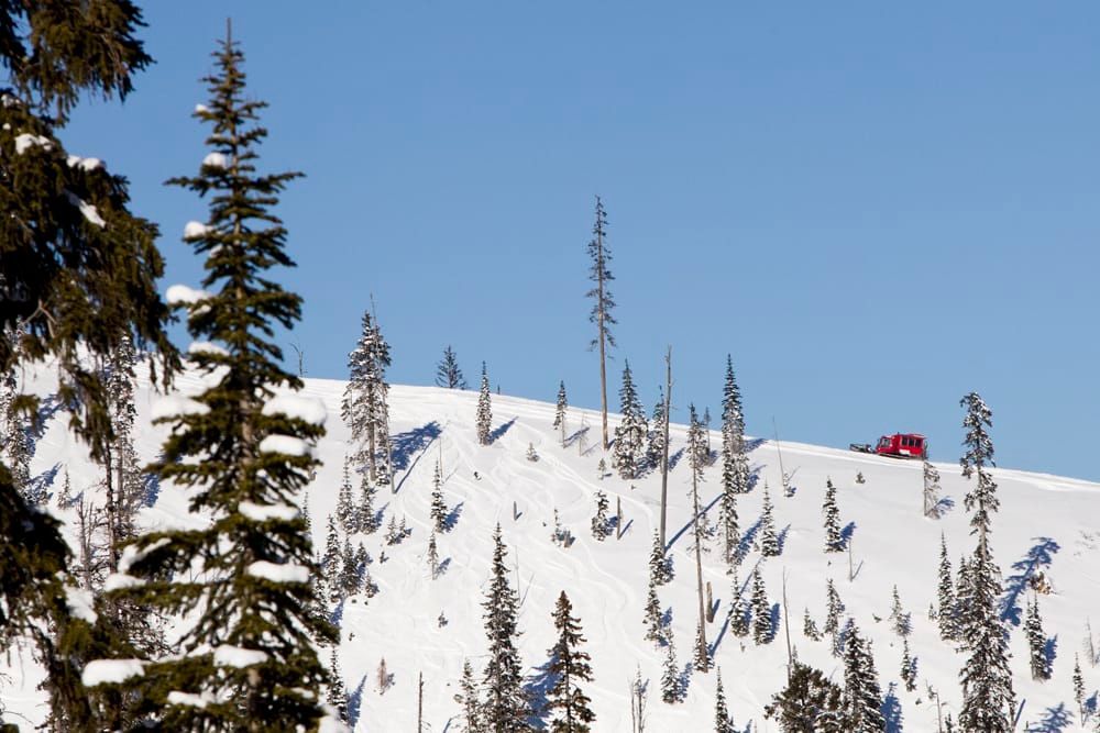 A red car is driving down a snow covered mountain