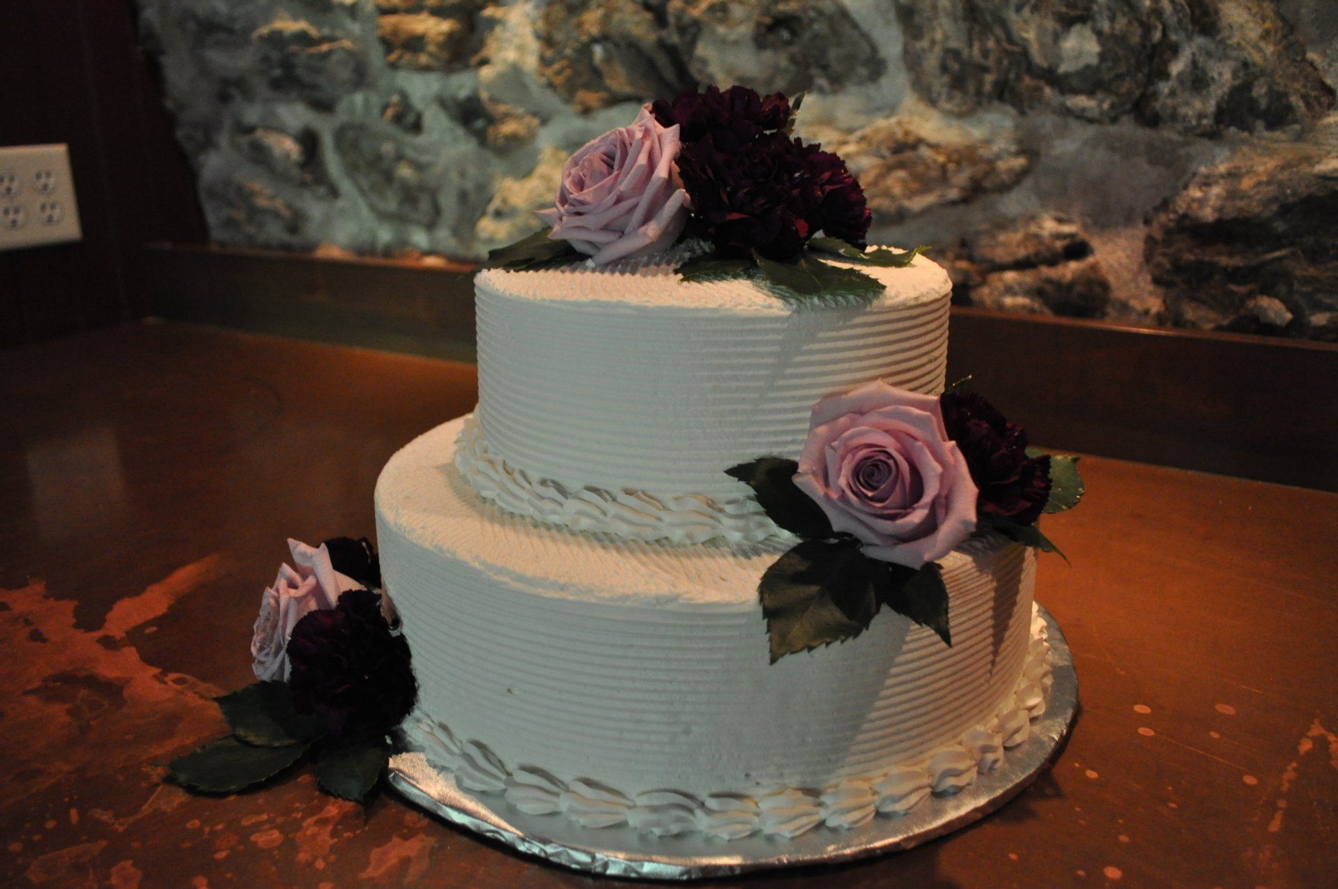 A white cake with purple roses on top of it