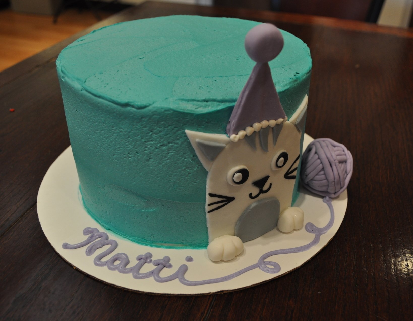A birthday cake for matti with a cat wearing a party hat