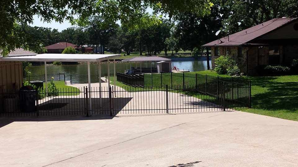A driveway leading to a house with a carport and a lake in the background