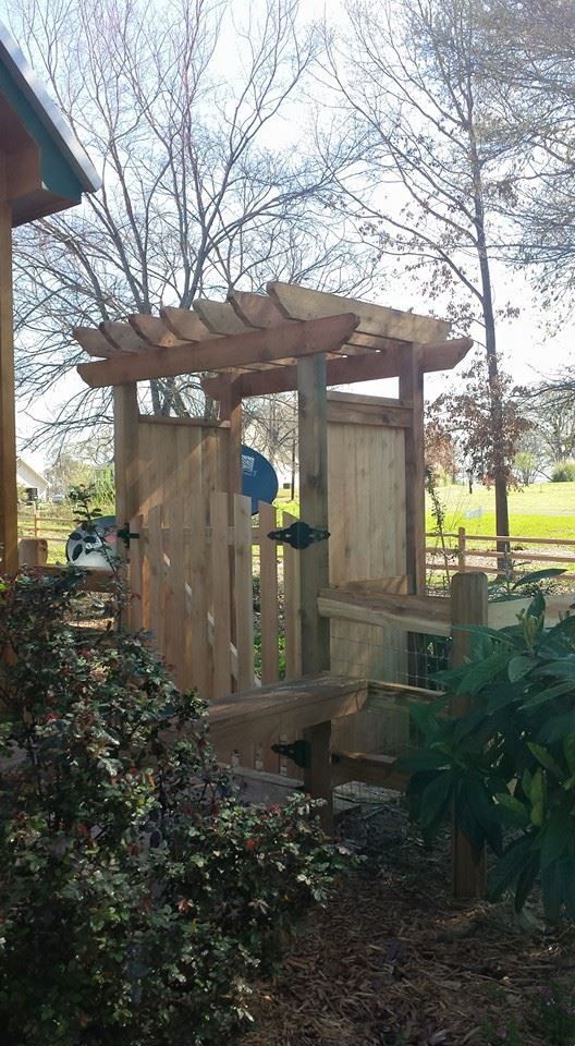 A wooden fence with a pergola and a gate in the backyard.