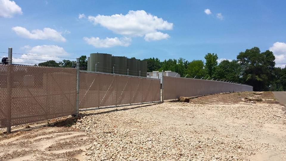 A large fence is surrounding a dirt field.