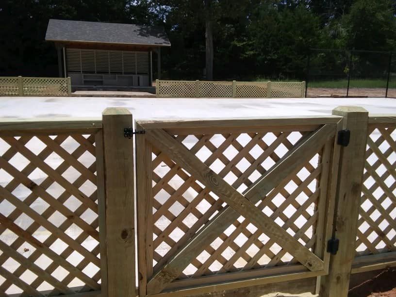 A wooden lattice fence with a gate in front of a building