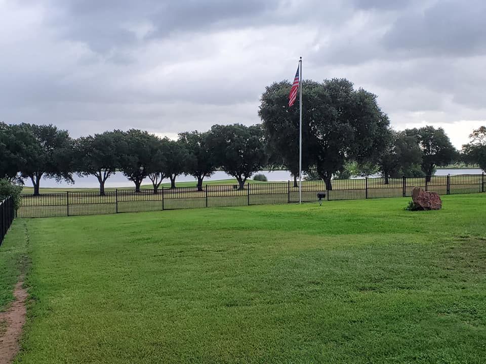 A large grassy field with trees in the background and a flag in the foreground