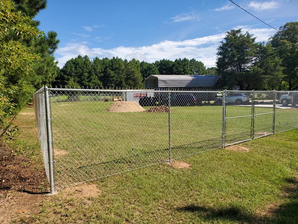 A chain link fence is surrounding a grassy field.