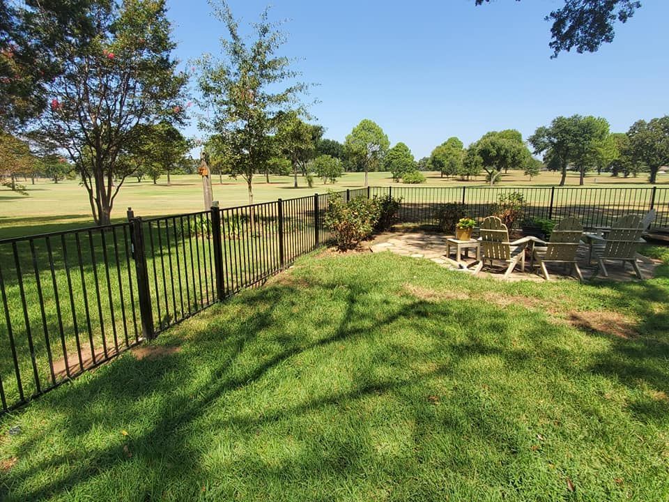 A backyard with a wrought iron fence and a fire pit.