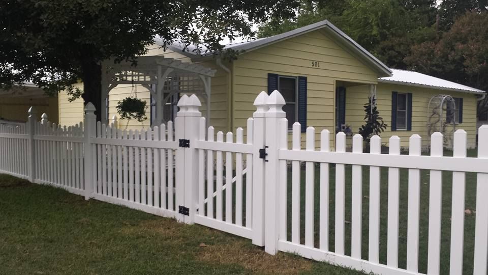 A white picket fence surrounds a yellow house