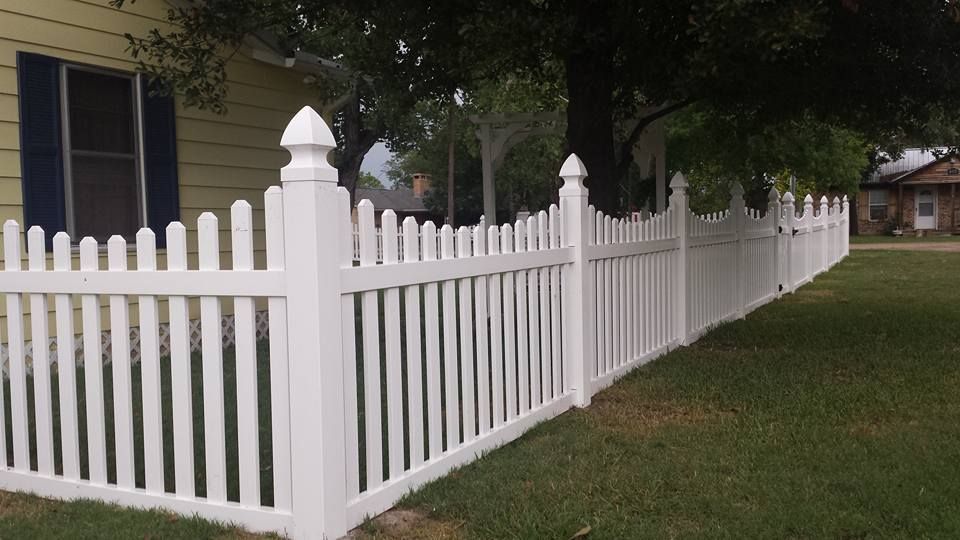 A white picket fence is in front of a house.