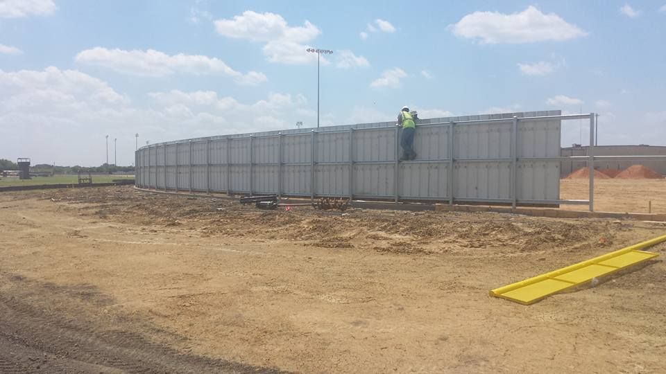 A man is standing on top of a fence in a field.