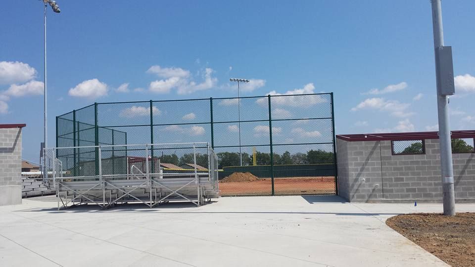 A baseball field with a fence and bleachers on a sunny day.