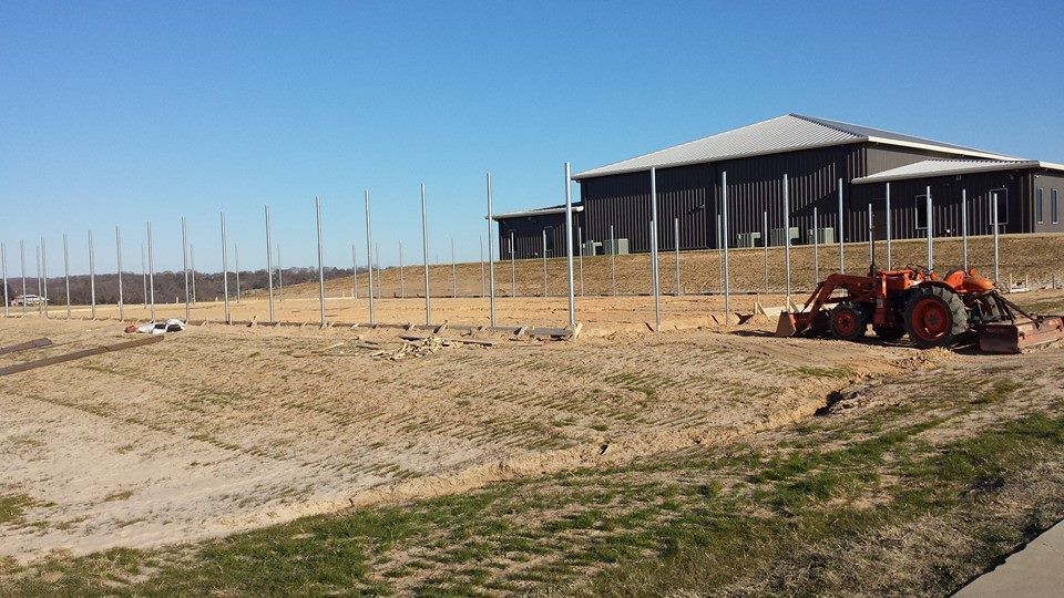 A tractor is parked in a field in front of a building.
