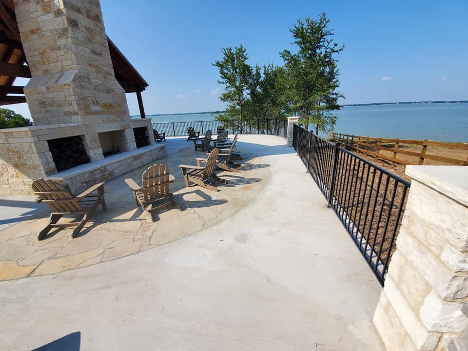 A patio with chairs and a fireplace overlooking the water