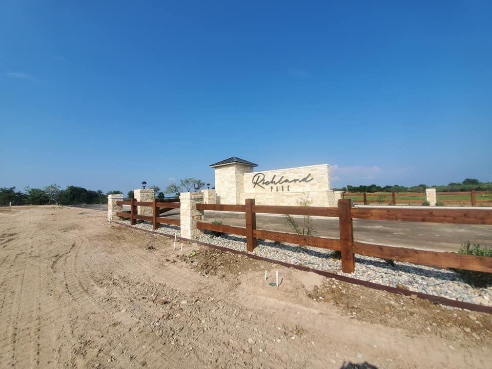 A wooden fence surrounds a dirt road in front of a sign that says reliant