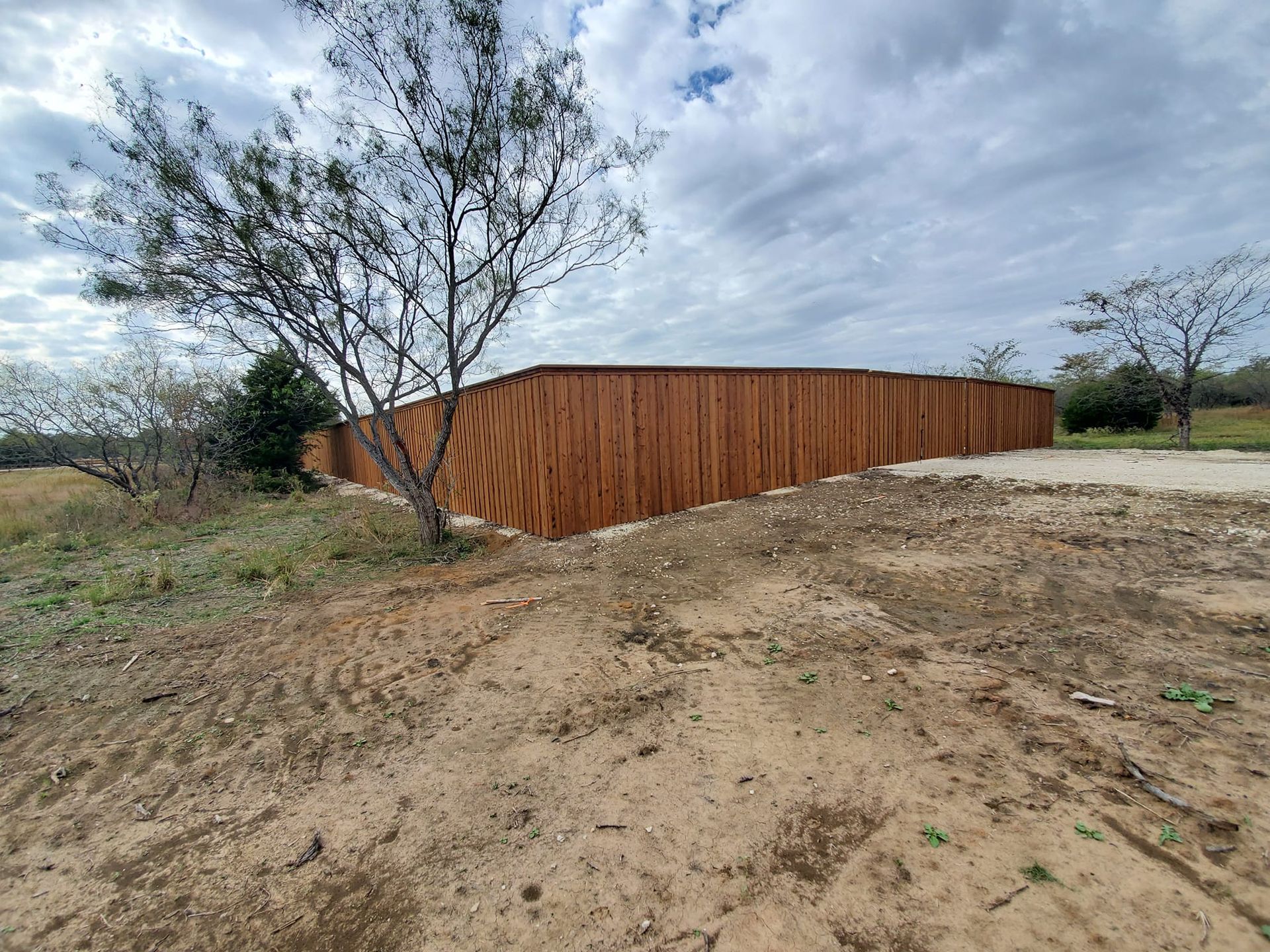 A wooden fence is sitting in the middle of a dirt field.