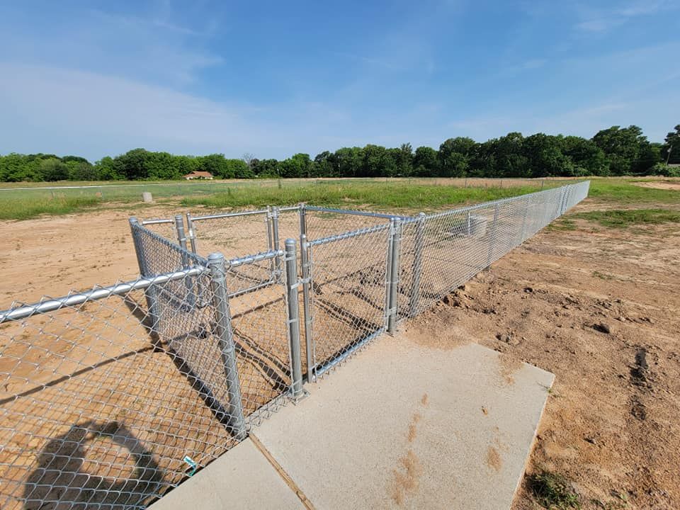 A chain link fence is surrounding a concrete structure in a field.