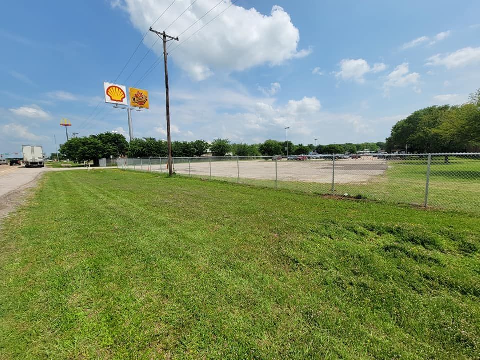 A grassy field with a fence and a sign that says shell on it.