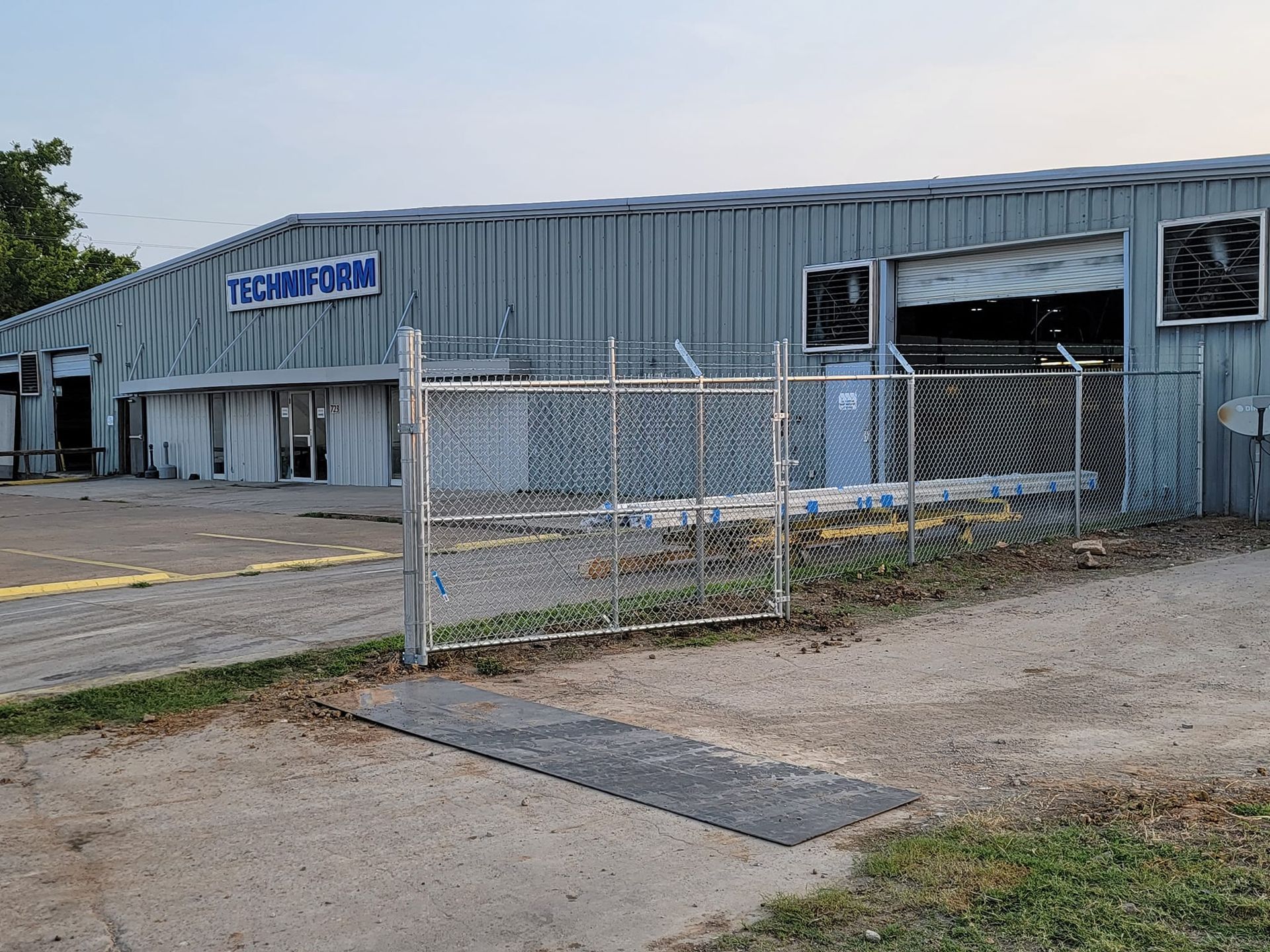 A large metal building with a chain link fence in front of it.