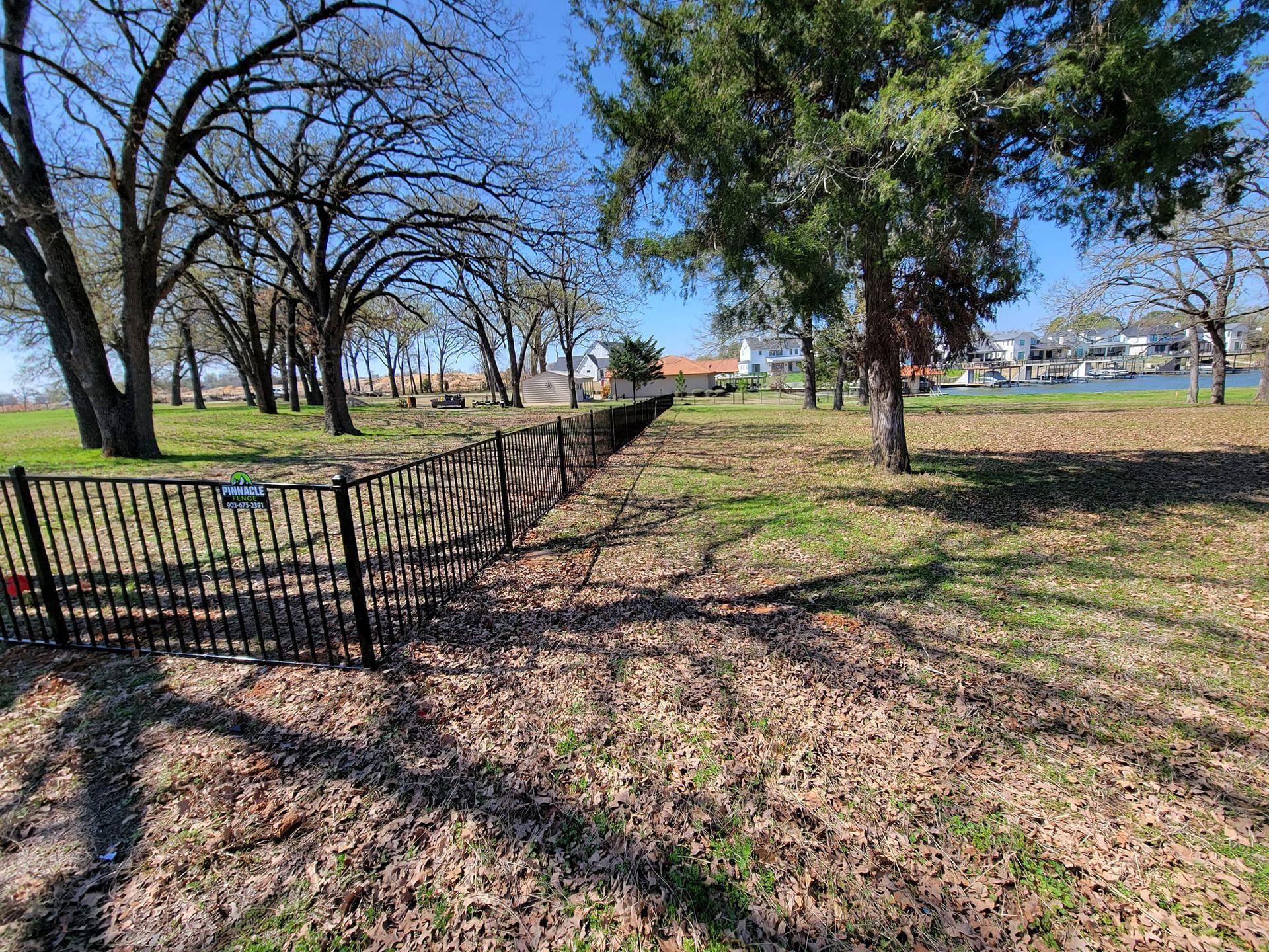 There is a fence in the middle of a field with trees in the background.