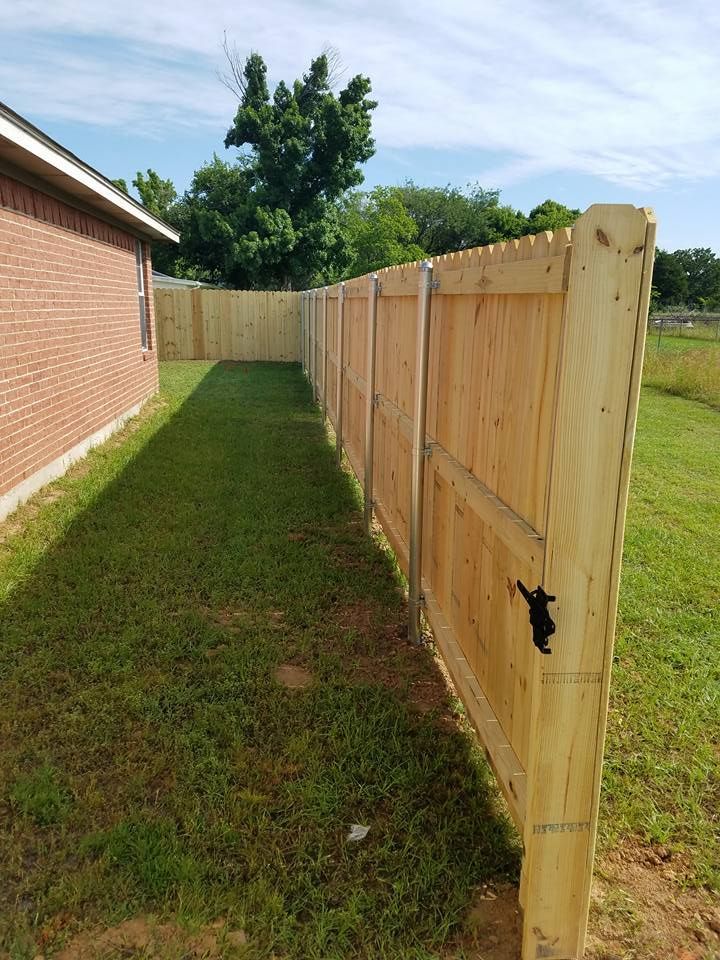 A wooden fence is in the backyard of a house.