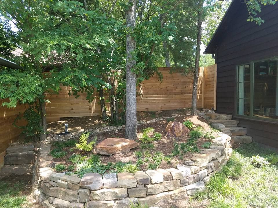 There is a stone wall in the backyard of a house.
