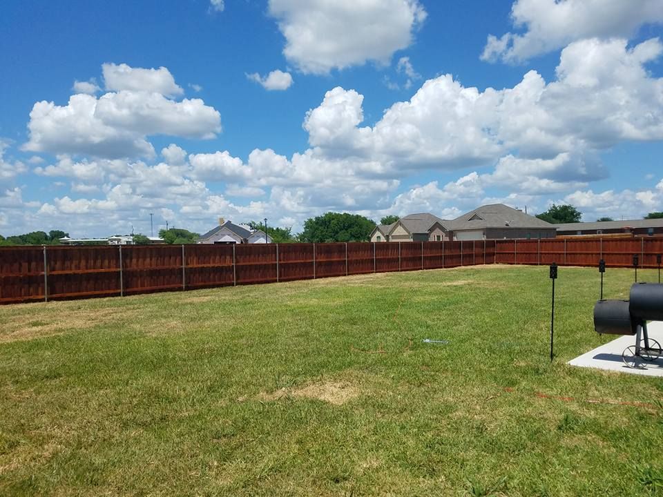 A backyard with a wooden fence and a grill.